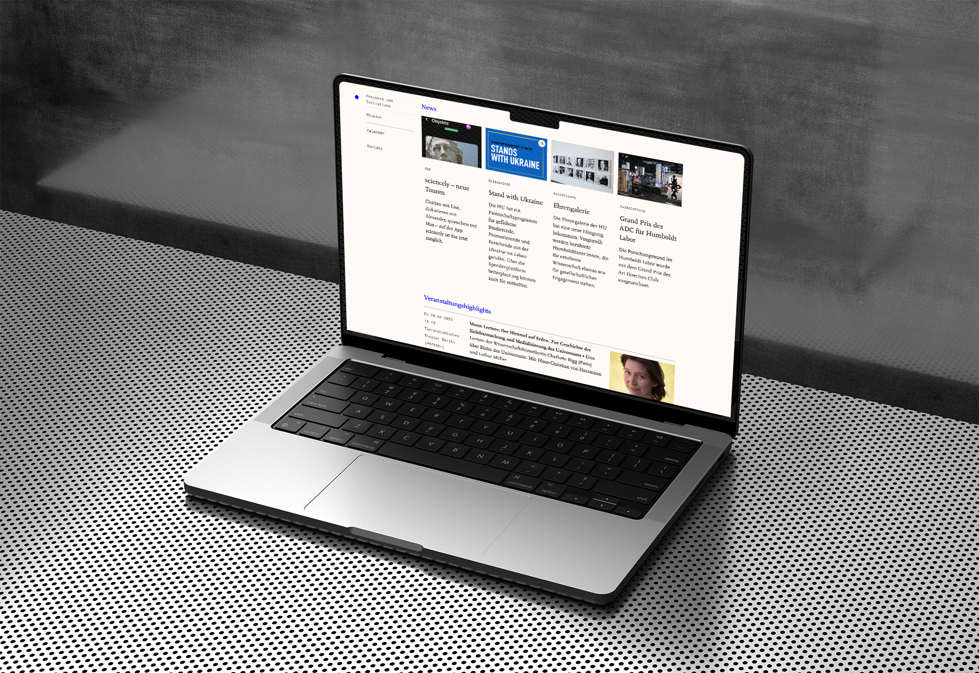 A mockup of a laptop in a cool metallic environment showing a clean page in grey tones featuring some event tiles.